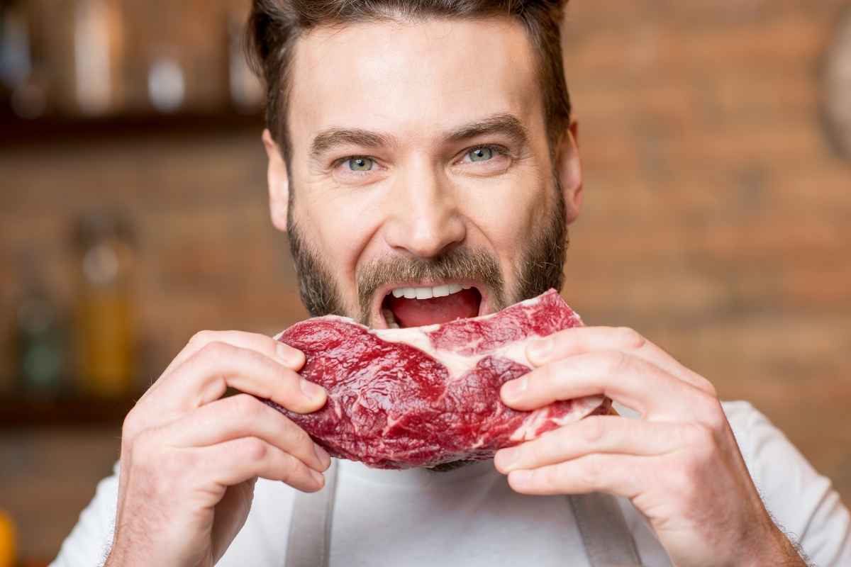 uomo mangia una bistecca cruda