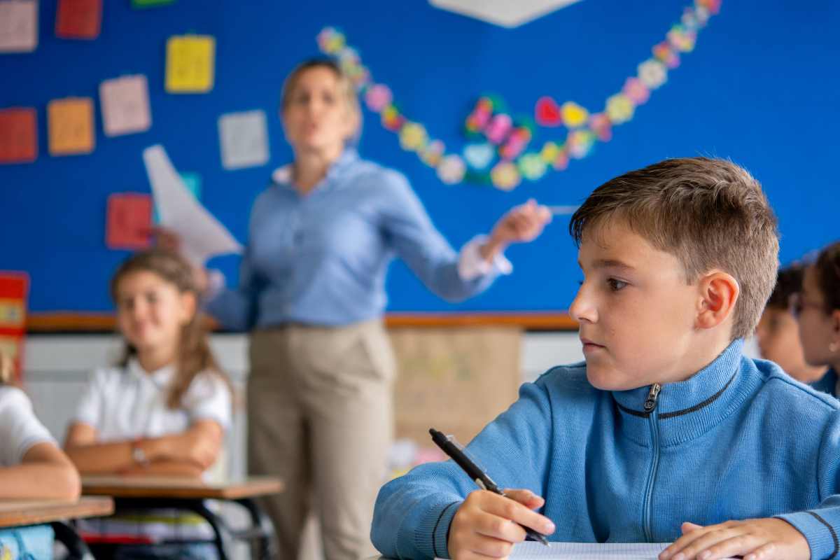 un bambino in primo piano in classe mentre scrive