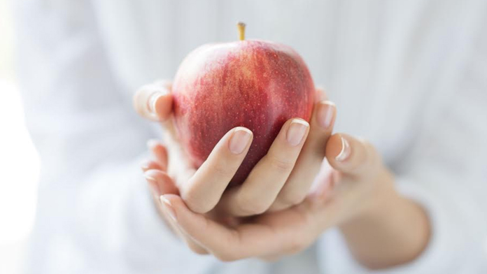 L'immagine di una mela in mano a una donna