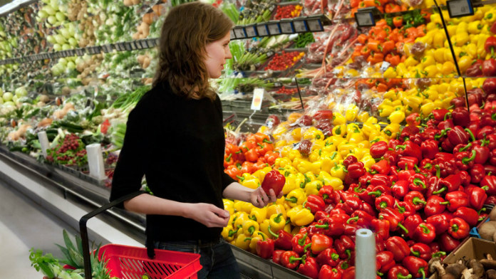 una donna sceglie quale verdura acquistare in un supermercato