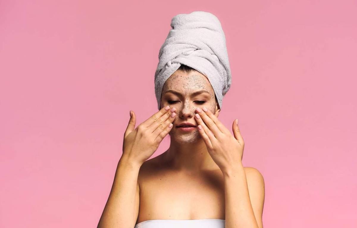 una donna si mette della crema sul viso dopo la doccia