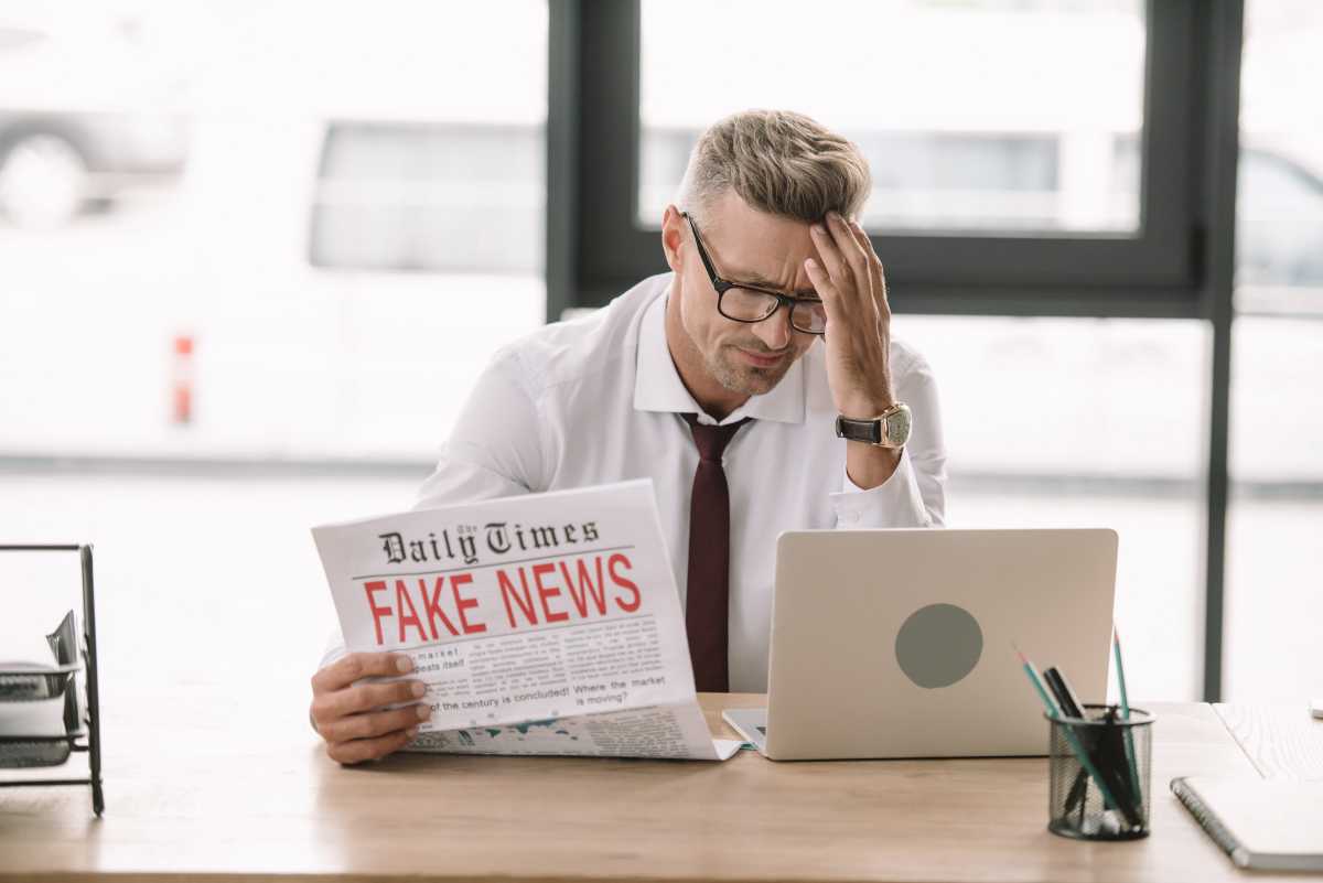 un uomo legge un giornale con il titolo fake news