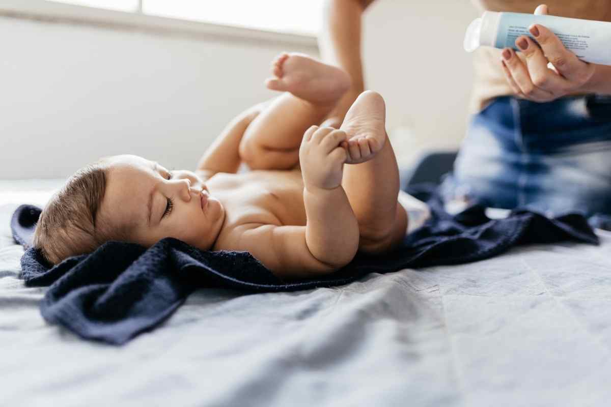 una mamma spalma della pomata sul sederino di un bambino