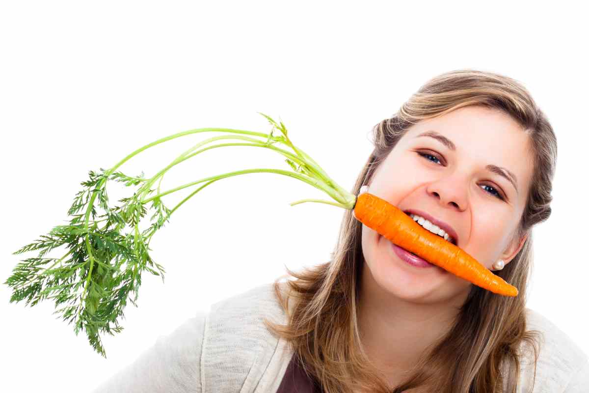 una ragazza con una carota in bocca