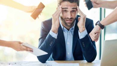 uomo d'affari stressato circondato da persone che gli mostrano device elettronici