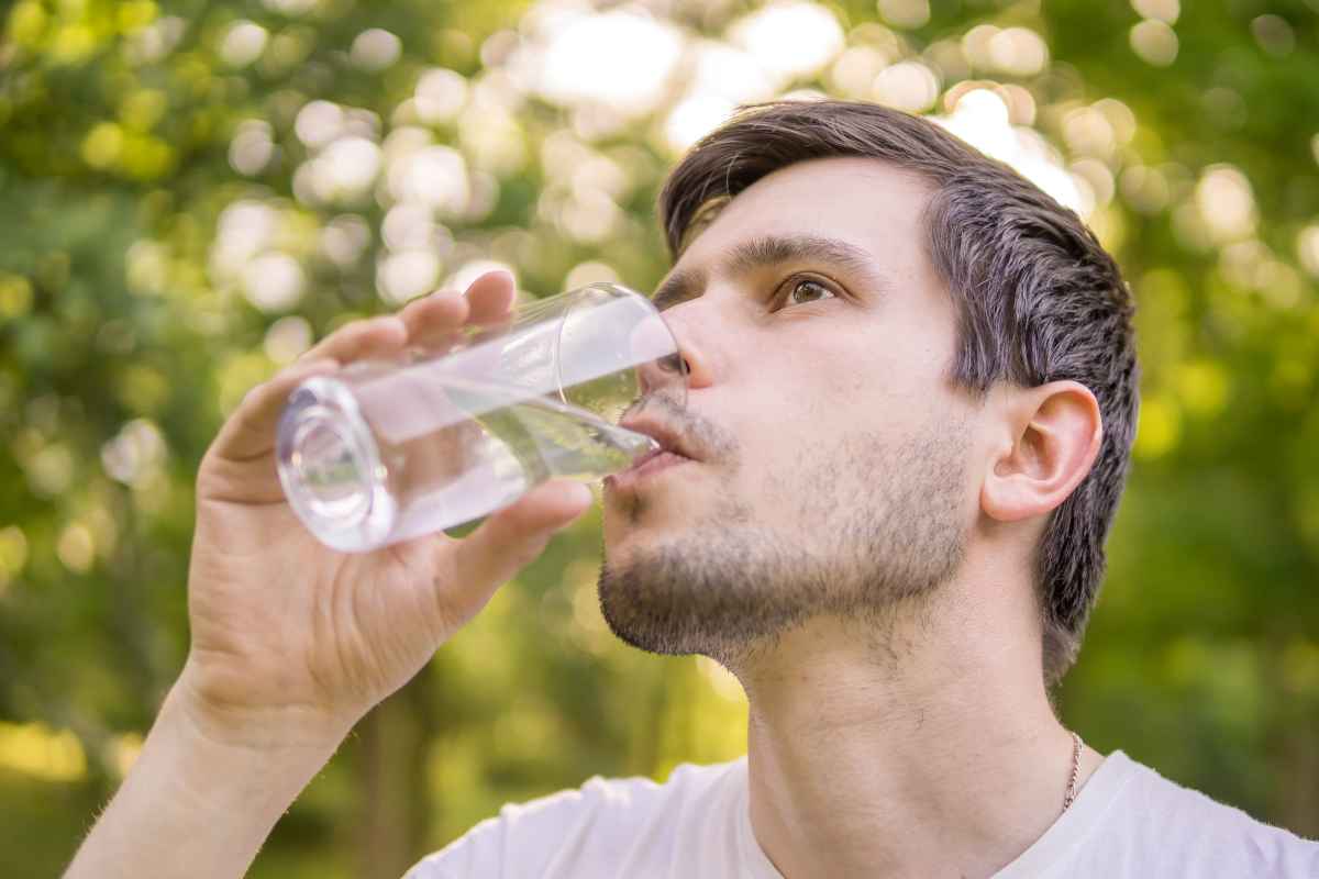 un ragazzo beve un bicchiere di acqua dopo aver fatto sport