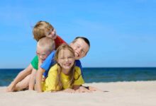 quattro bambini uno sull'altro giocano in spiaggia