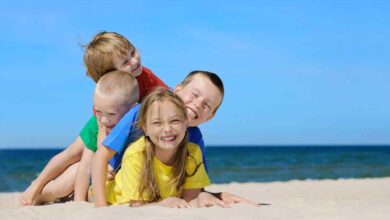 quattro bambini uno sull'altro giocano in spiaggia