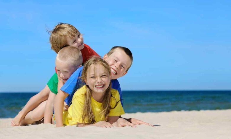quattro bambini uno sull'altro giocano in spiaggia