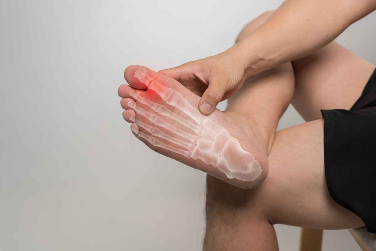 un uomo si tocca l'alluce rotto