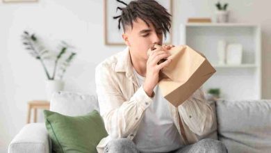 un uomo respira in un sacchetto di carta per calmare l'iperventilazione