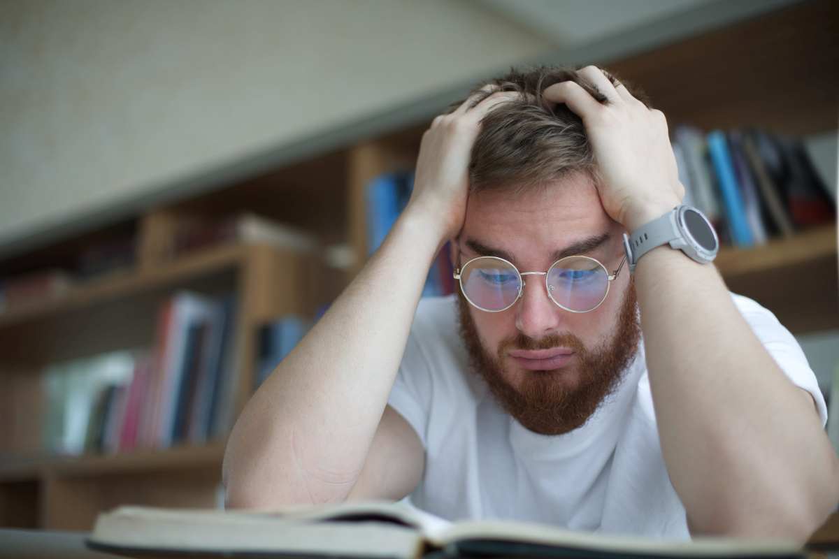un ragazzo sembra disperato davanti ai libri