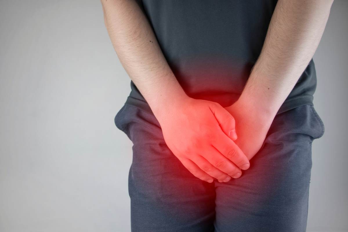 uomo che si mette le mani incrociate sui genitali come se avesse dolore
