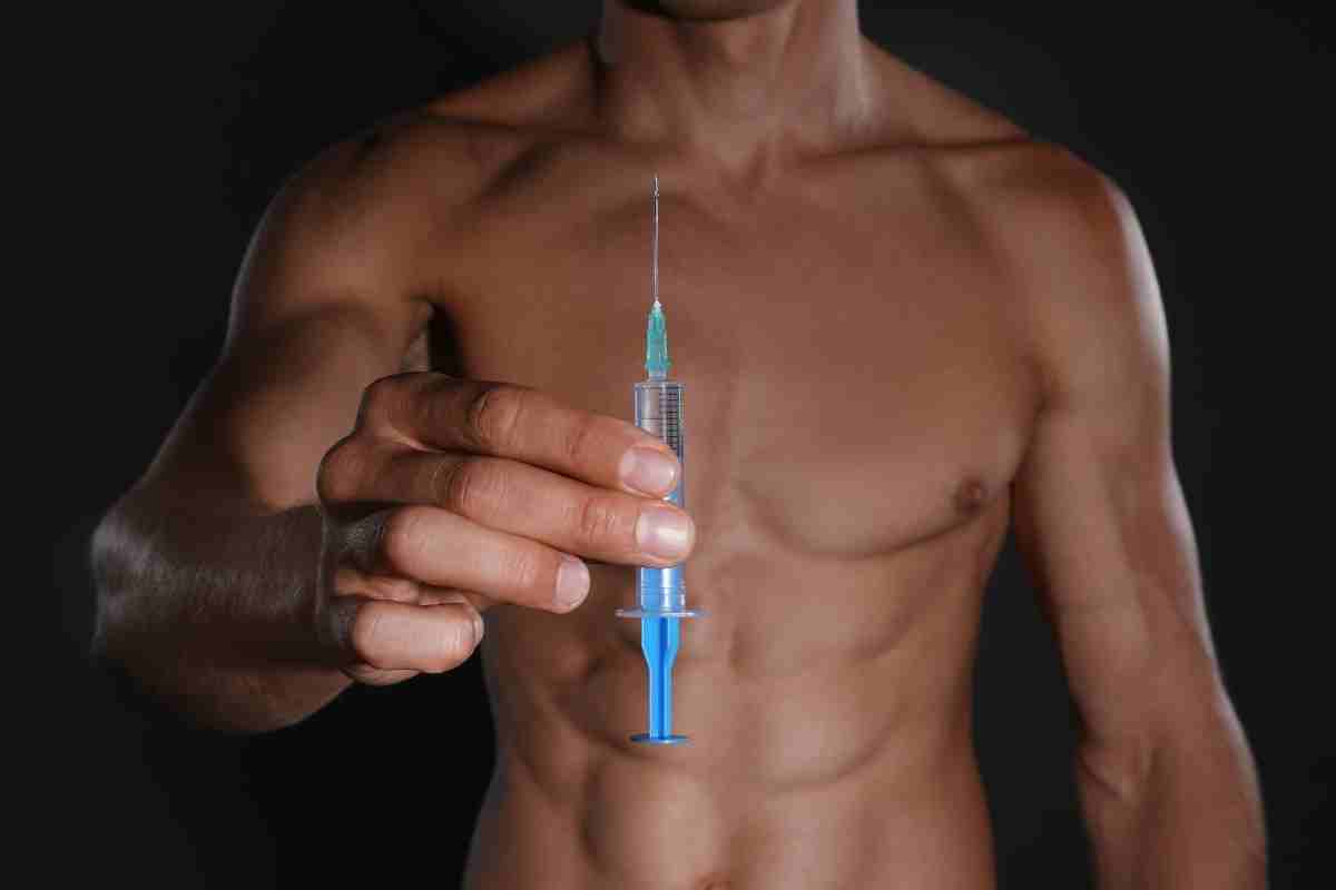 un atleta a torso nudo ha in mano una siringa