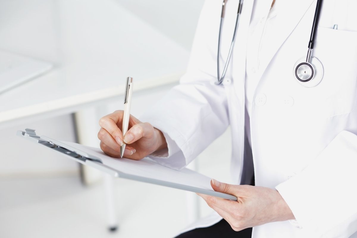 un medico scrive sulla sua cartelletta le indicazioni per il paziente