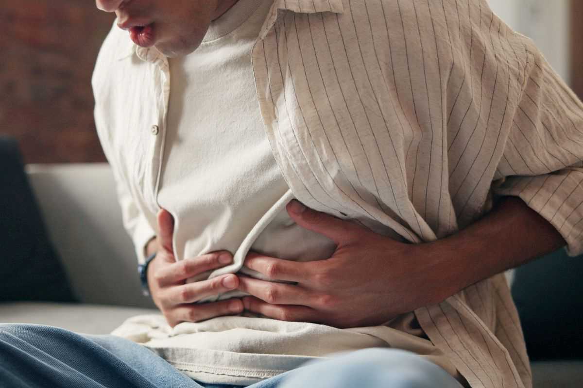 uomo che si mette le mani sull'addome perché ha dolore