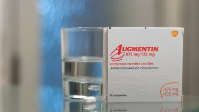 una confezione di augmentin con un bicchiere di acqua