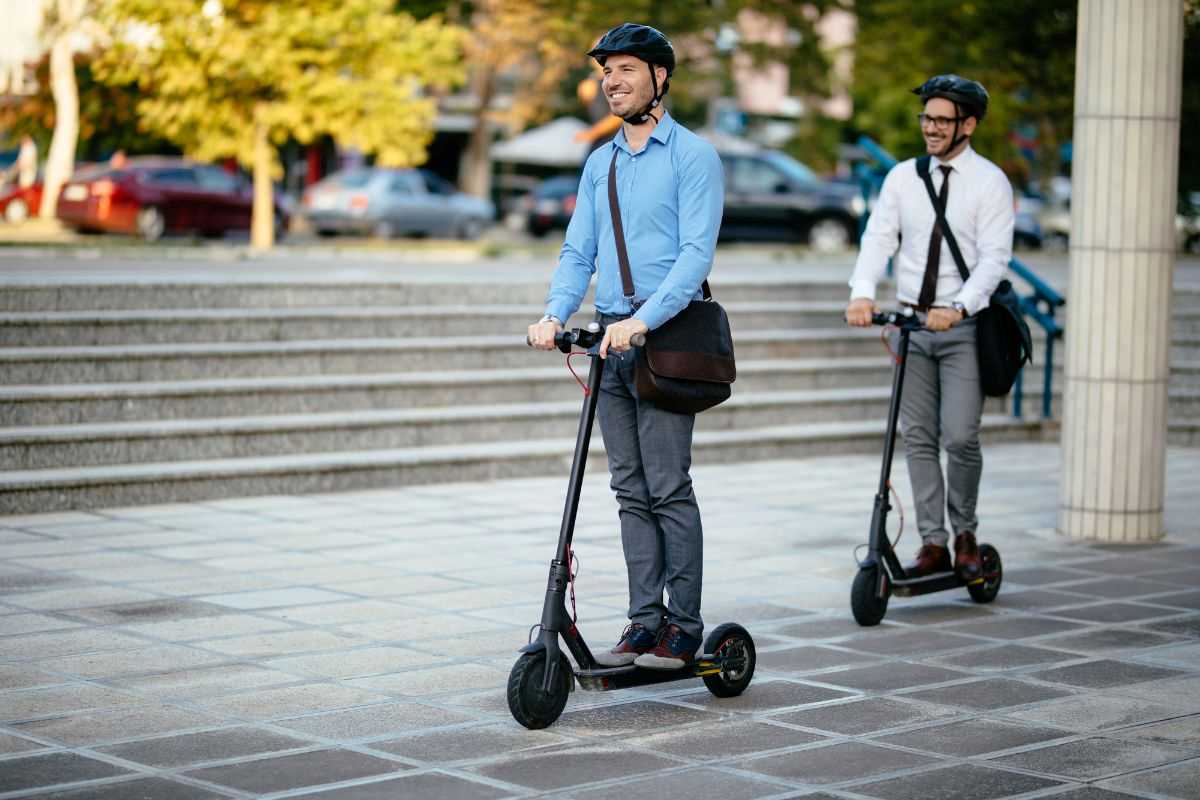 due uomini viaggiano sul monopattino elettrico indossando il casco