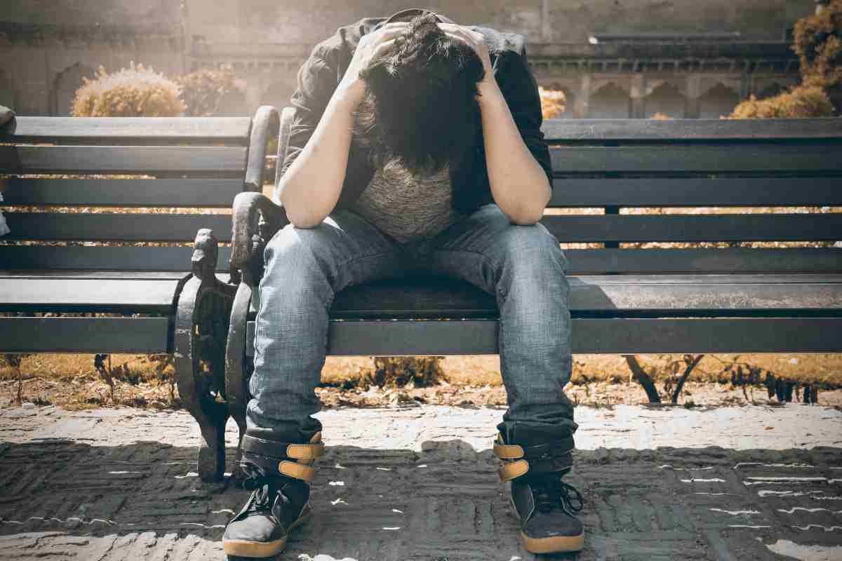 un ragazzo disperato sulla panchina in un parco