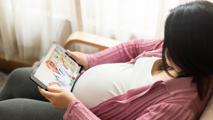 una donna incinta guarda un video mentre attende il vaccino materno contro il virus sinciziale