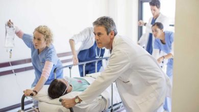 equipe di medici che in ospedale spinge velocemente una barella con su una donna intubata che ha leucemia fulminante