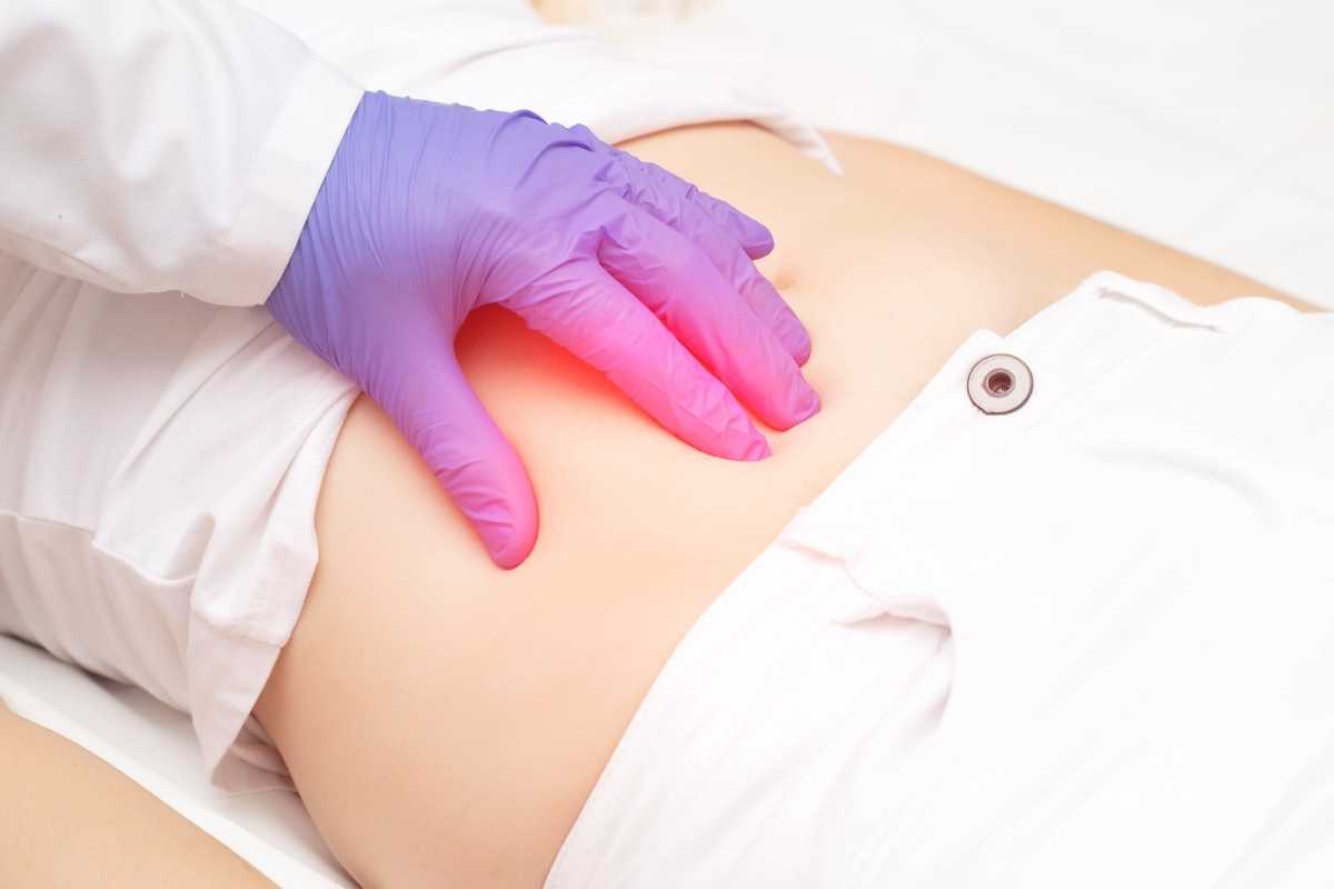 un medico procede alla palpazione dell'addome di una paziente