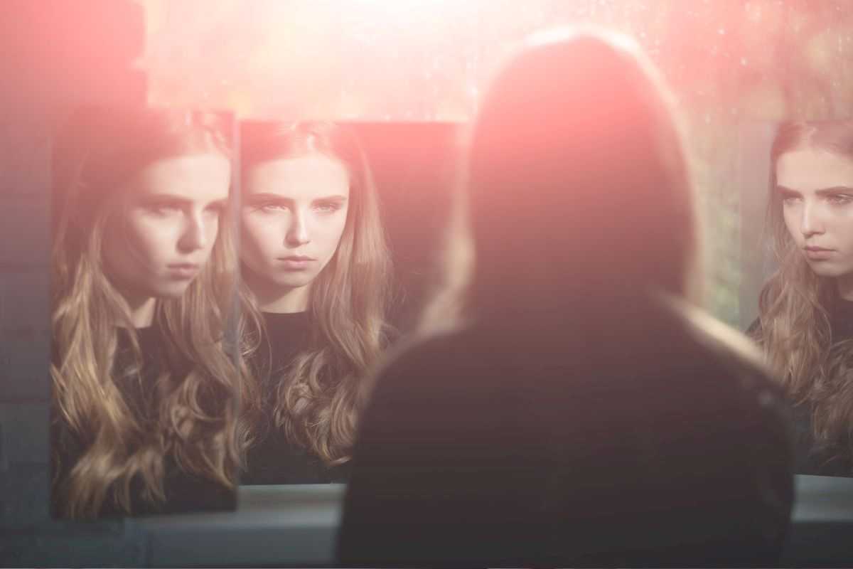 ragazza giovane con dismorfofobia la cui immagine viene proiettata su tanti specchi