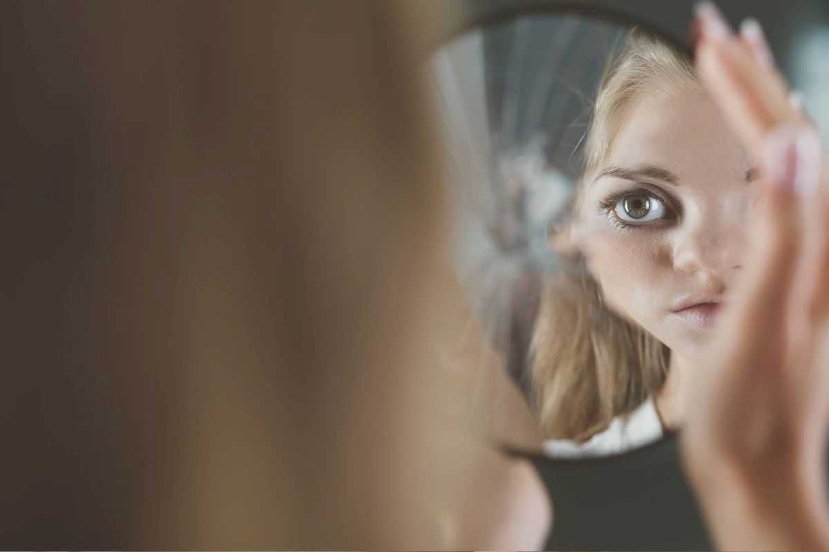ragazza che si specchia e la sua immagine viene riflessa deformata