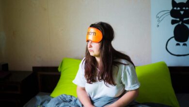 una ragazza seduta sul letto che non riesce a dormire