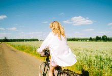 una ragazza pedala in campagna in un giorno estivo
