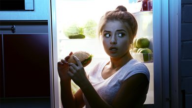 donna con fame notturna davanti al frigorifero per mangiare di nascosto