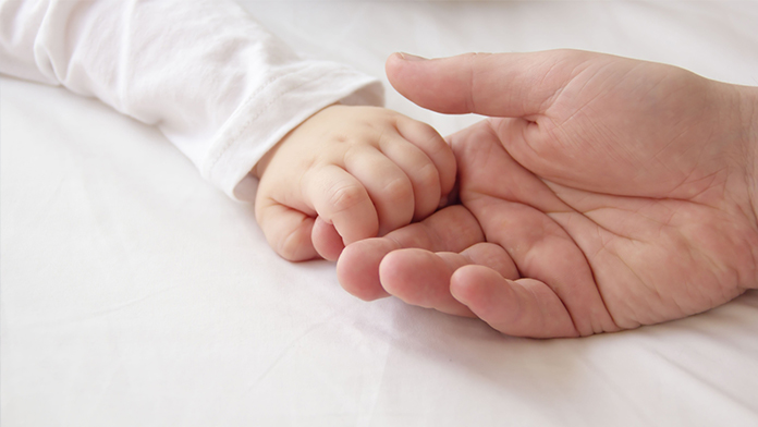 Una mamma stringe la mano a un bambino piccolo