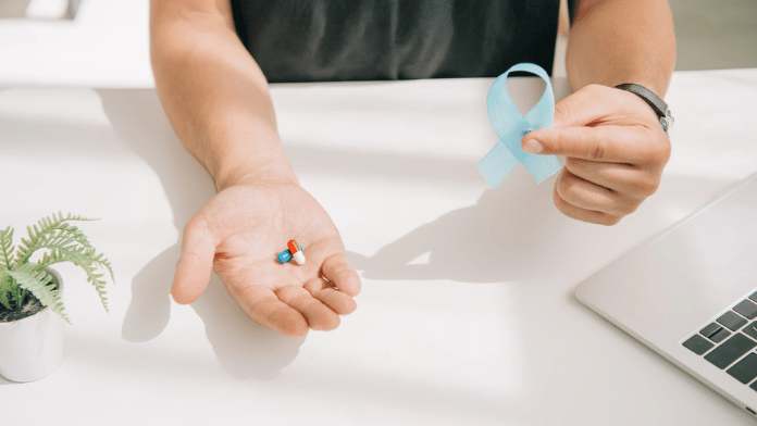Un uomo mostra il simbolo della lotta contro il tumore della prostata prima di assumere la terapia