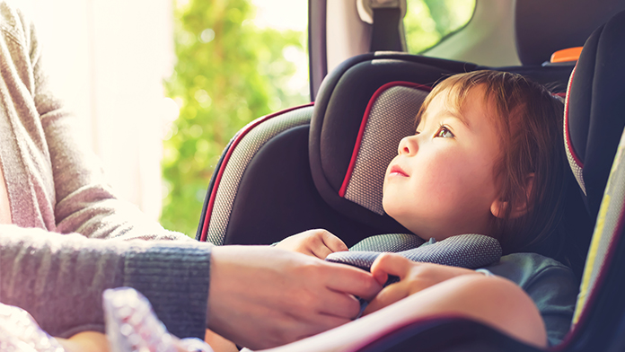 una mamma lega il bambino al seggiolino in macchina