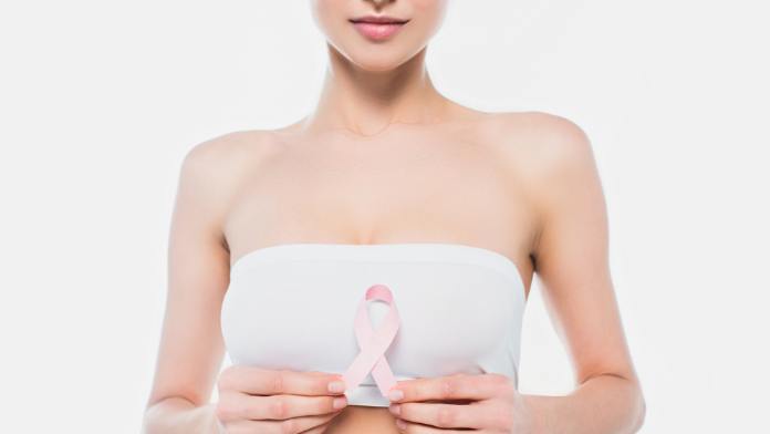 Donna con tumore al seno triplo negativo tiene in mano il fiocchetto rosa, simbolo della lotta contro il cancro al seno