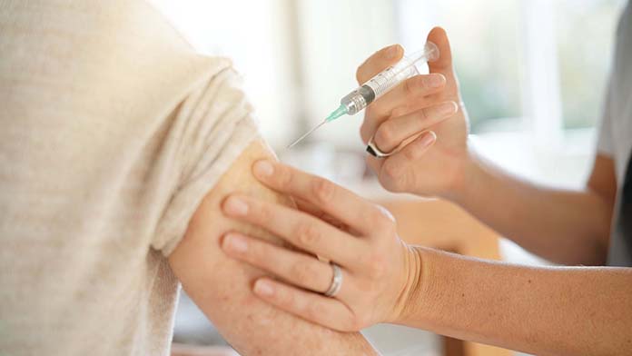 Un medico inietta il vaccino nel braccio di una persona anziana