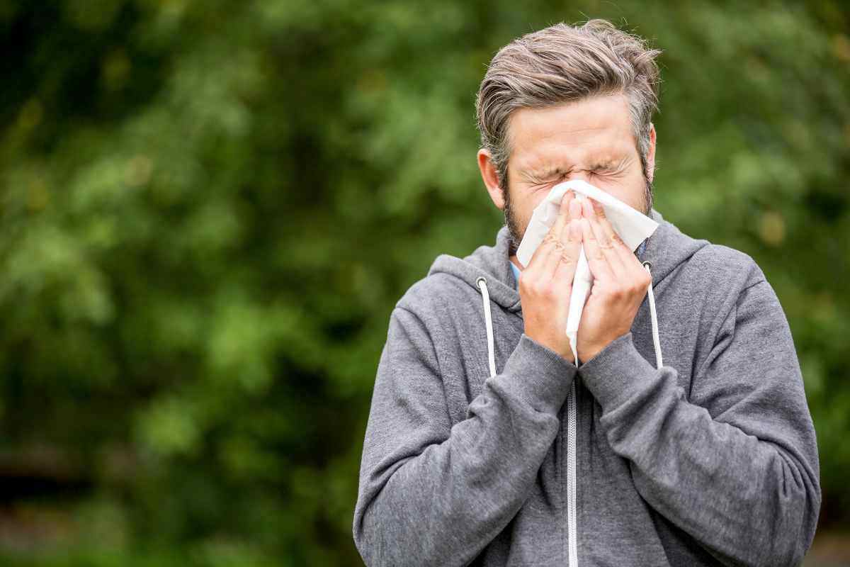un uomo si soffia il naso in un prato