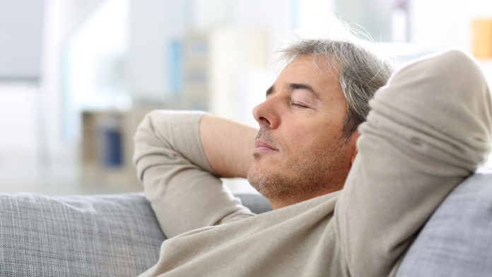 uomo sul divano intento a dormire dopo pranzo