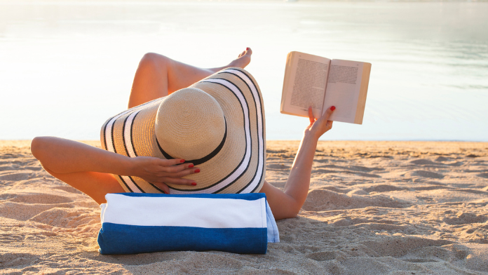 donna in spiaggia che legge uno dei libri da portare in vacanza