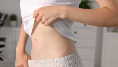 donna che tira su la maglietta per mostrare la pancia piatta