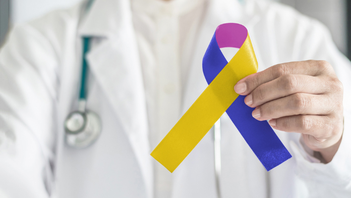 dottore tiene in mano il fiocchetto giallo e blu simbolo del tumore della vescica