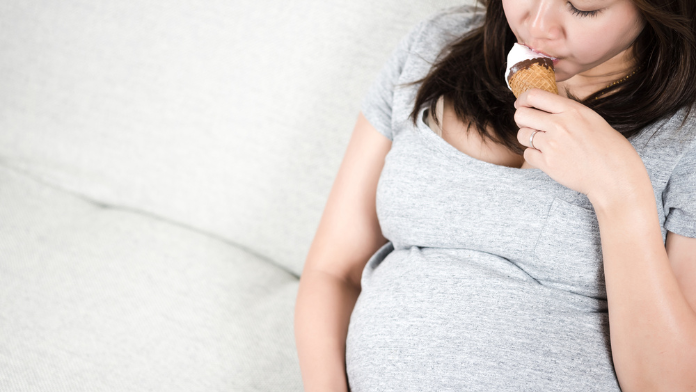 una giovane donna mangia un gelato in gravidanza