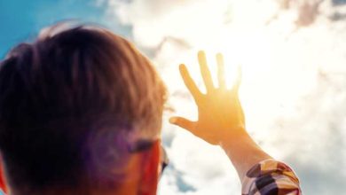 un uomo si ripara con una mano dai raggi del sole