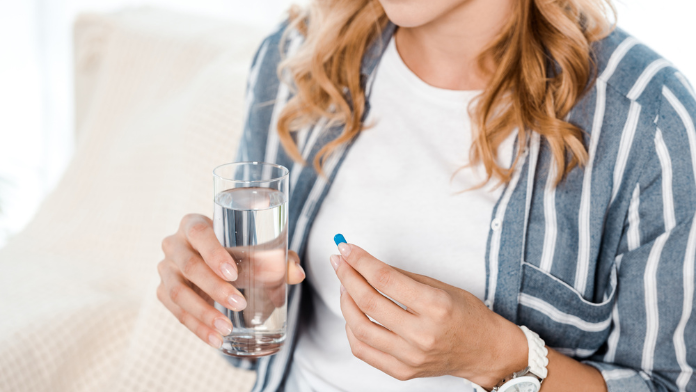 una donna sta per prendere una pillola con un bicchiere di acqua