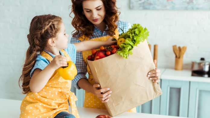 Una mamma mostra prodotti vegetali alla propria figlia