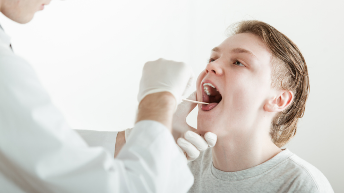 un medico controlla le tonsille di un giovane paziente