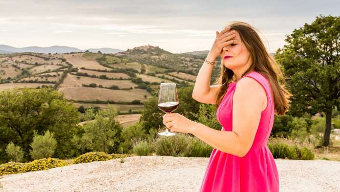 Una donna ha mal di testa dopo aver bevuto un bicchiere di vino rosso