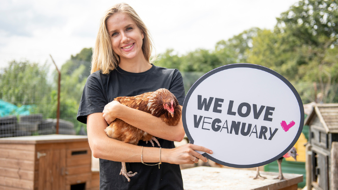 Una ragazza con un gallina in braccio sostiene il Veganuary