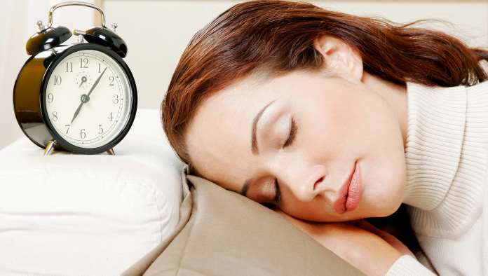una donna dorme vicino a una sveglia