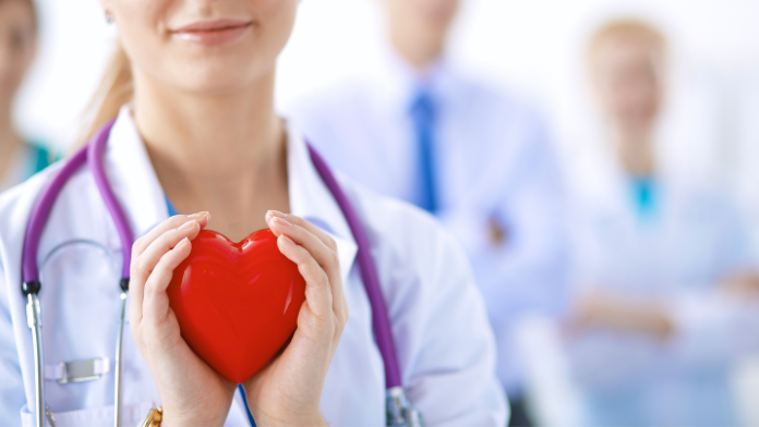 Una dottoressa tiene in mano un cuore e offre visite cardiologiche gratuite